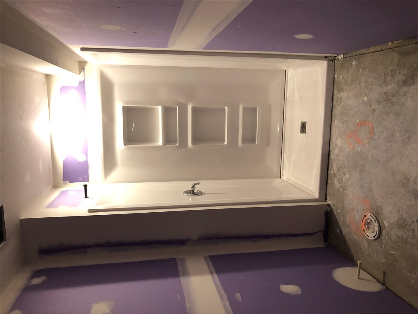 Walk-in shower mid-build: surround and niches set, floor and toilet not yet installed