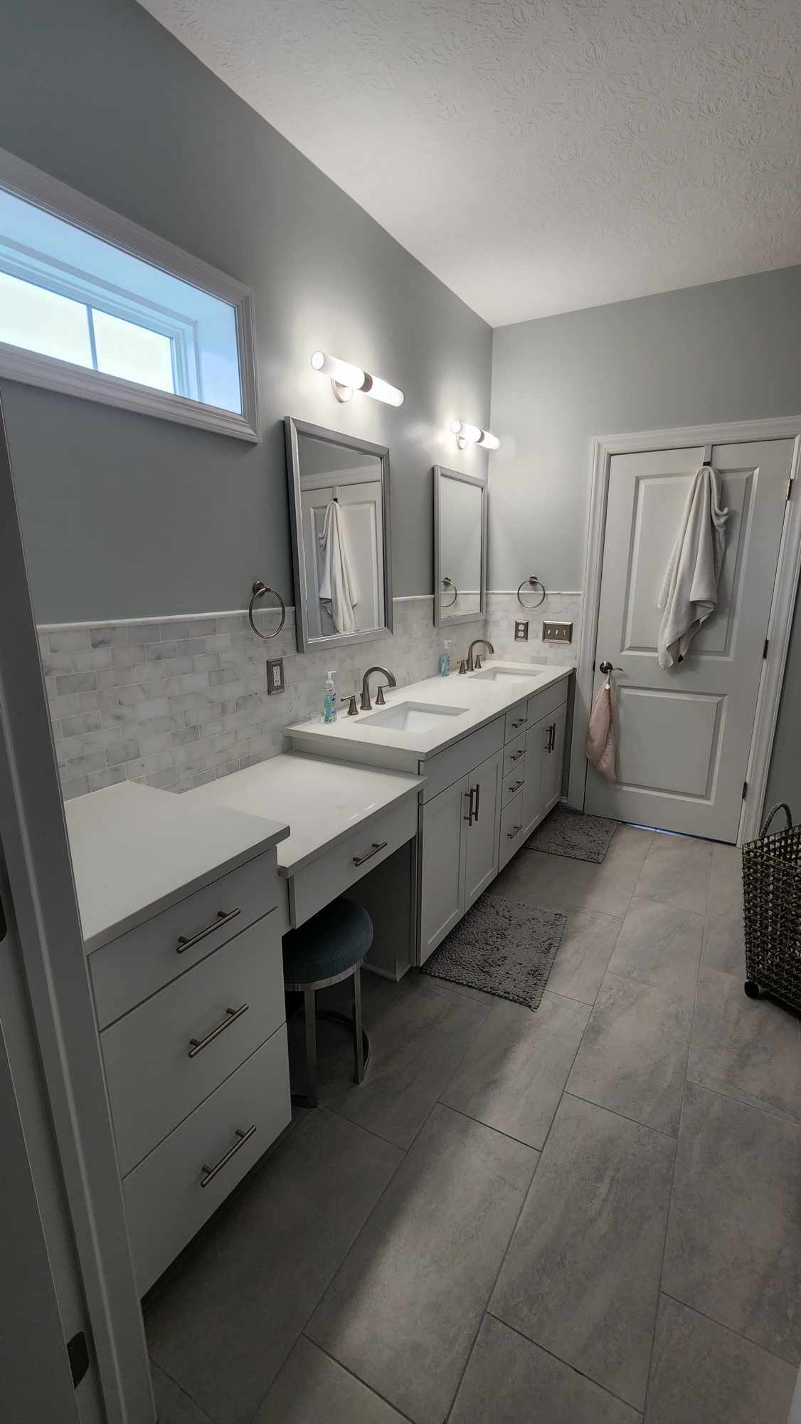 Double vanity run with quartz top, marble subway backsplash and makeup desk