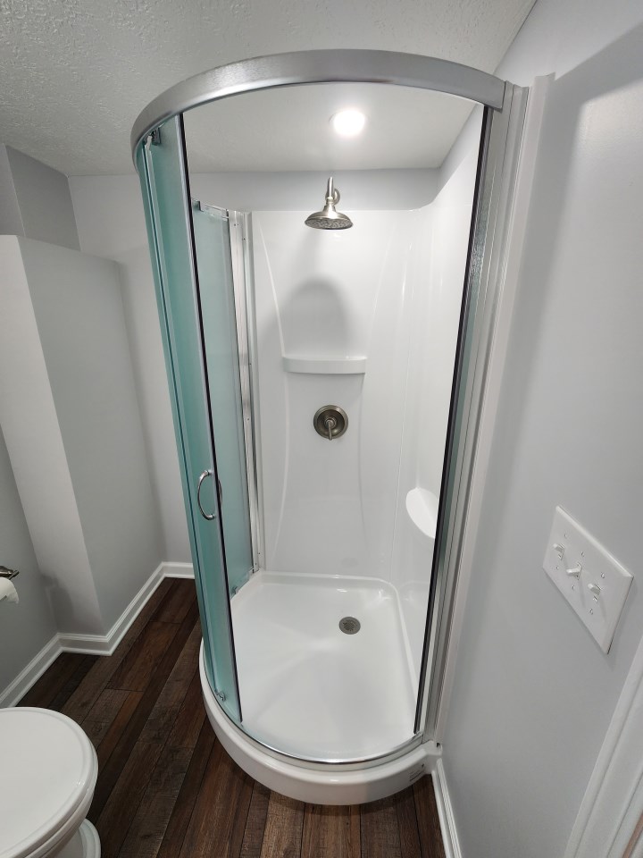 Corner shower stall with curved sliding glass doors and rain shower head